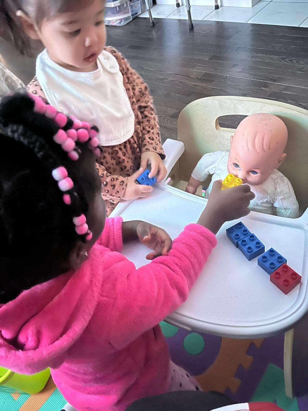 2 girls feeding a baby doll