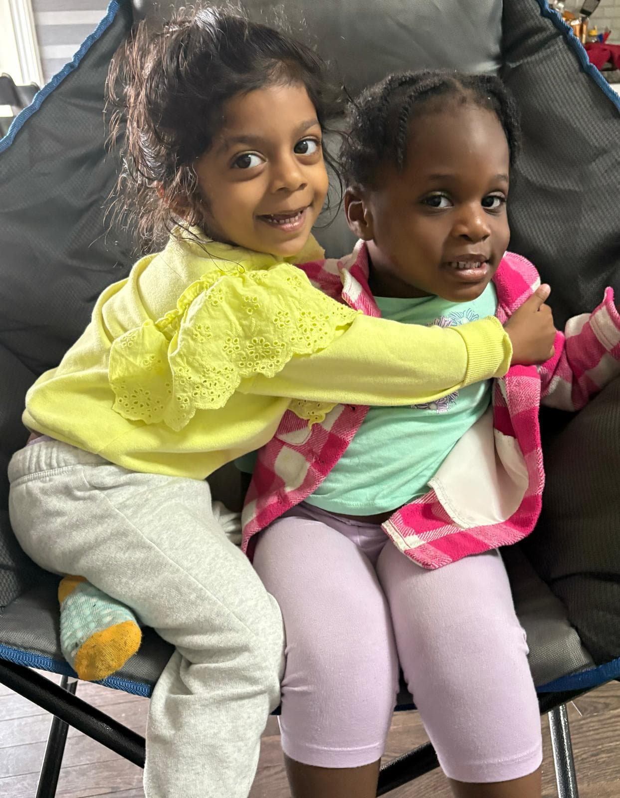 2 kids hugging and smiling for the camera on a chair