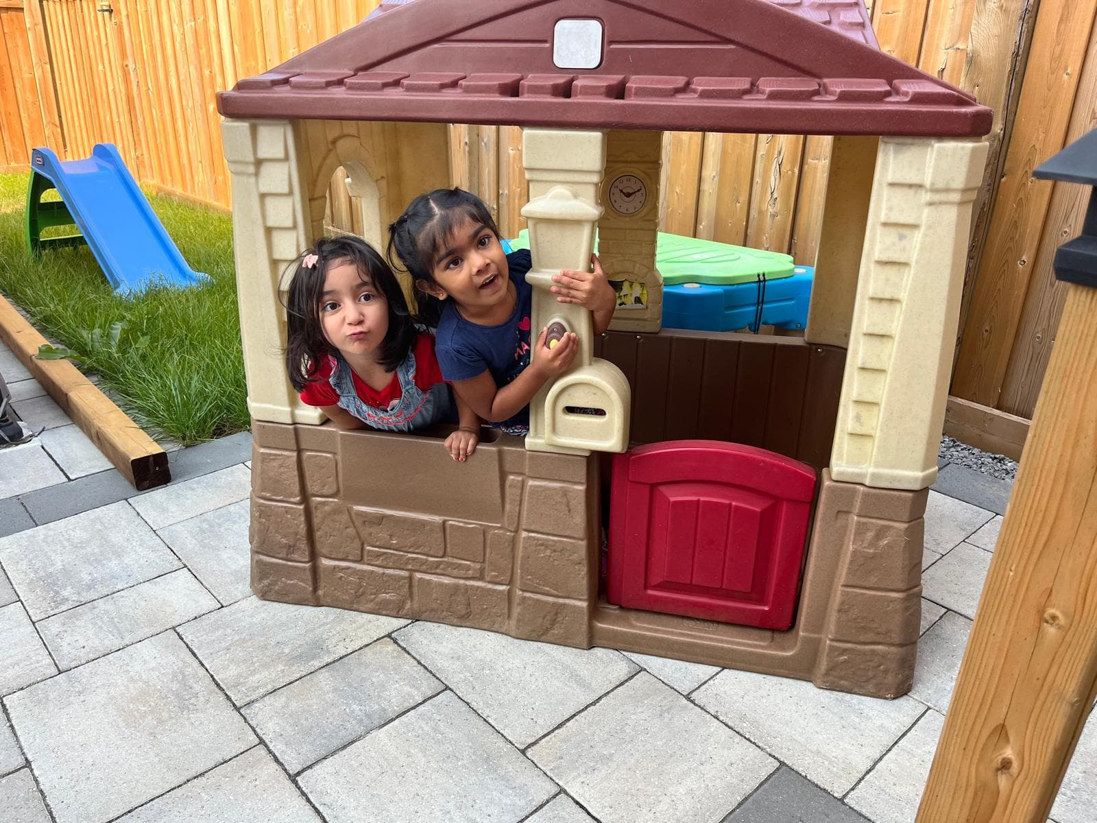 2 kids playing in outdoor mini house