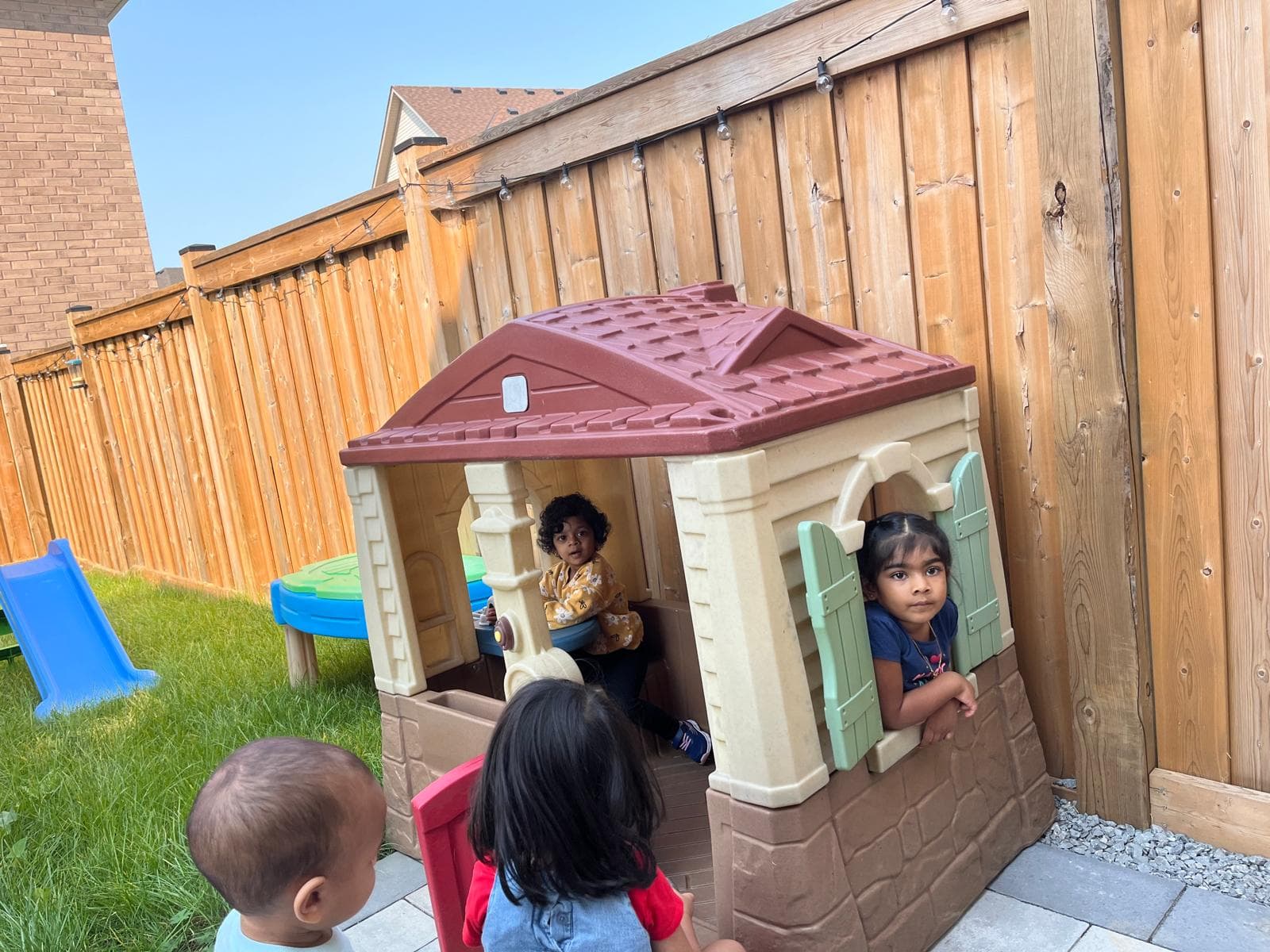 4 kids playing in outdoor mini house