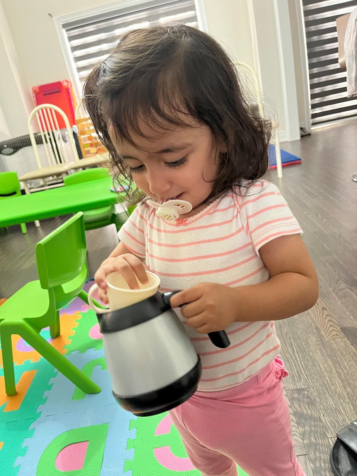 Funny picture of infant putting cup inside tea pot