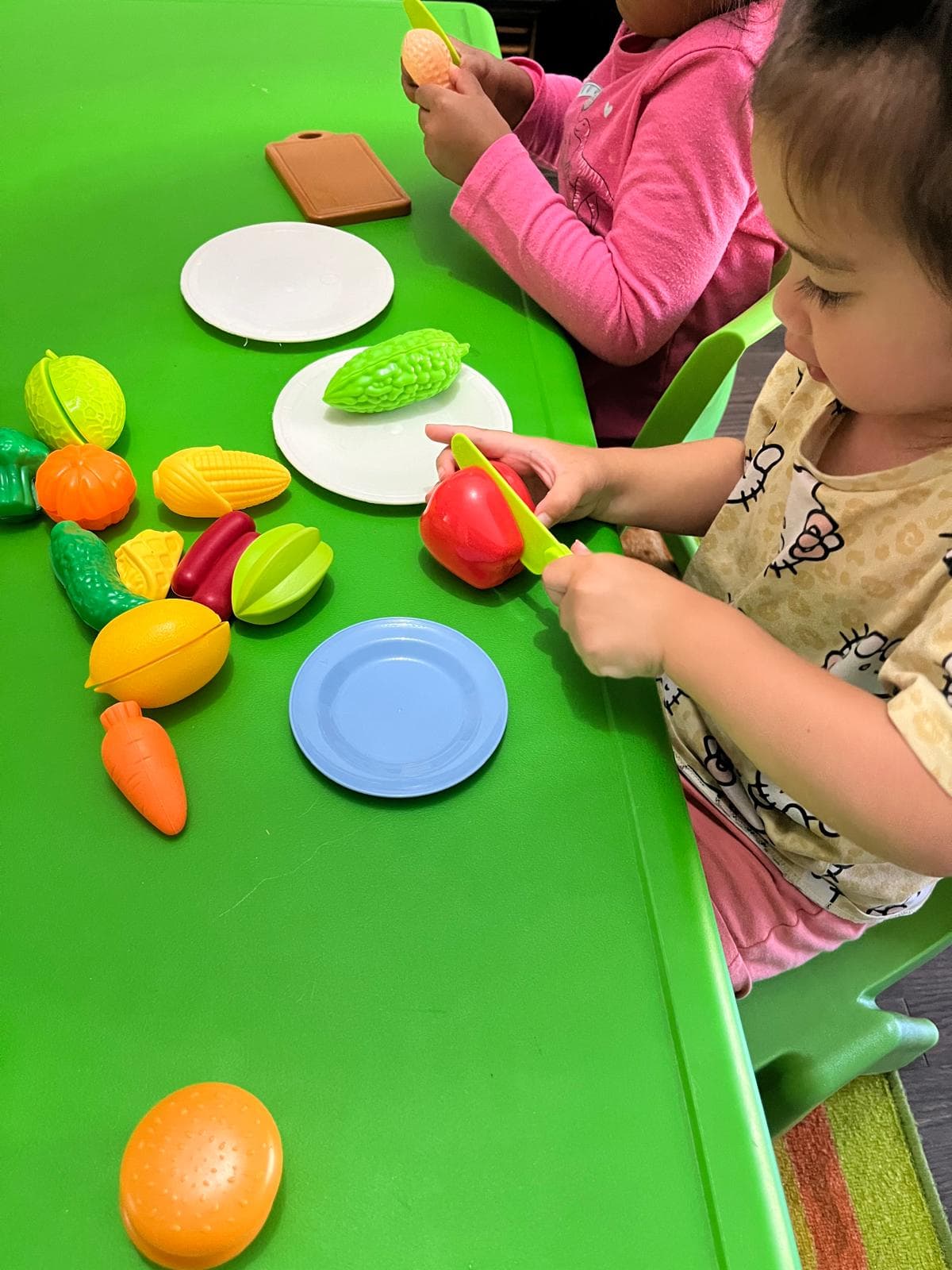 Infant cutting up toy vegetables