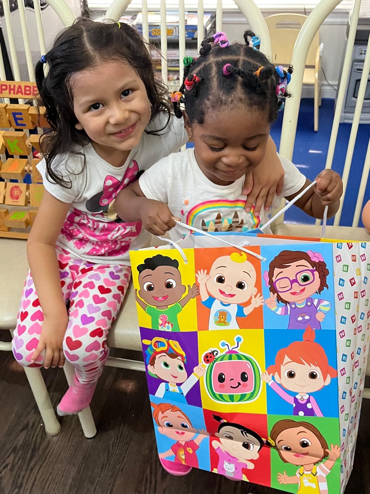 Kid hugging infant and smiling for camera with gift in hand